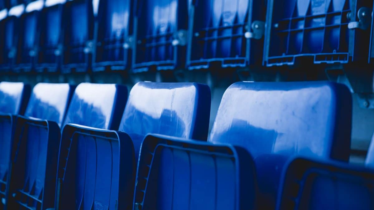 Close-up of empty blue stadium seats arranged in a repetitive pattern.