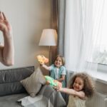 Father and children enjoying playful bonding time indoors, using water guns for fun and laughter.
