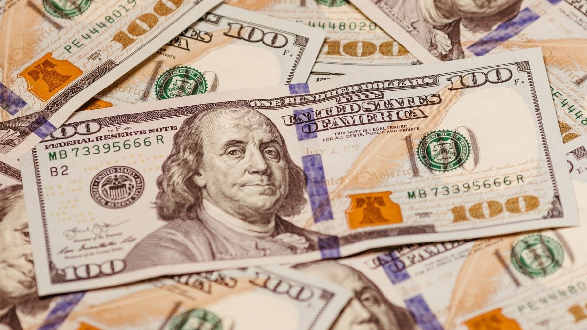 Close-up view of multiple US hundred dollar bills showcasing Benjamin Franklin.