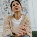 A woman in a cozy sweater is sitting indoors, expressing distress and frustration.