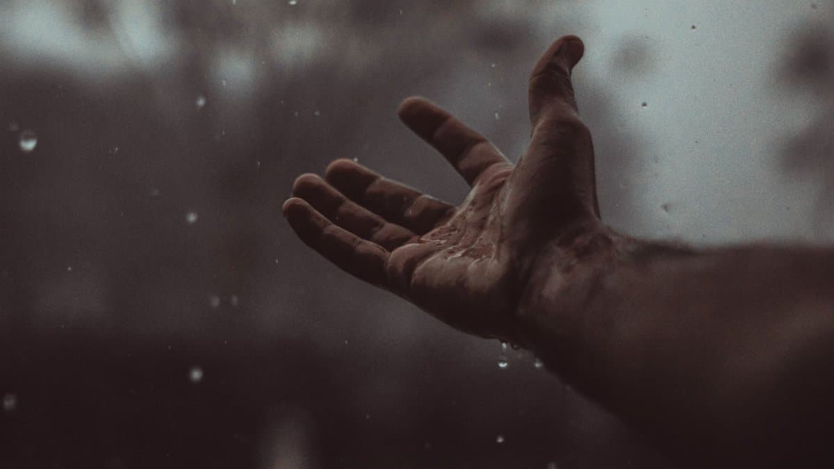 A close-up of a hand catching raindrops in Bahawalpur, embracing the rain's refreshing feel.