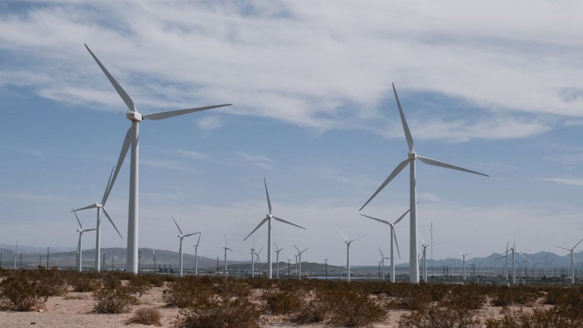 A scenic view of wind turbines in a desert, symbolizing clean, renewable energy technology.