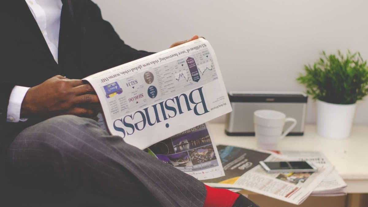 Businessman reading a financial newspaper at a desk, highlighting finance and commerce theme.