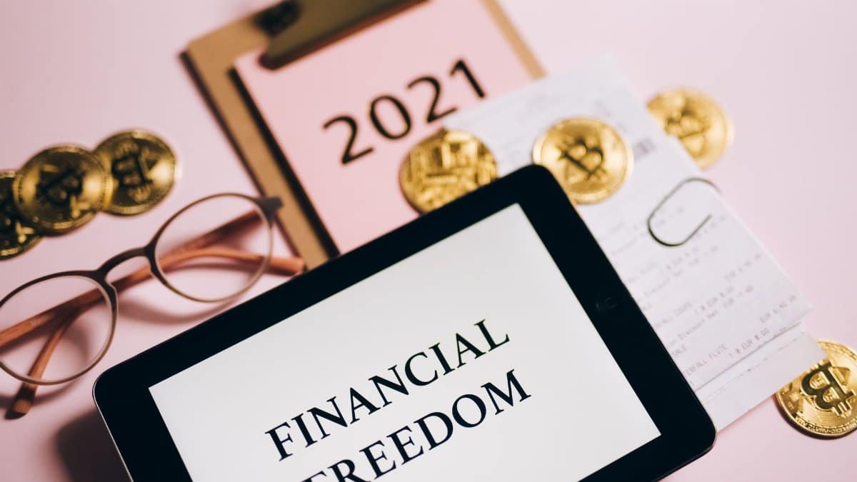 Tablet displaying 'Financial Freedom' surrounded by bitcoins and 2021 planner, symbolizing cryptocurrency potential.