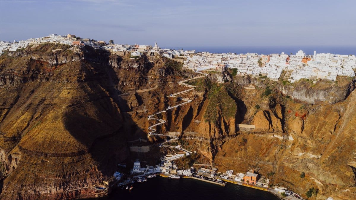 Stunning aerial view of Fira, Santorini with its iconic zigzag path on a cliffside overlooking the sea.
