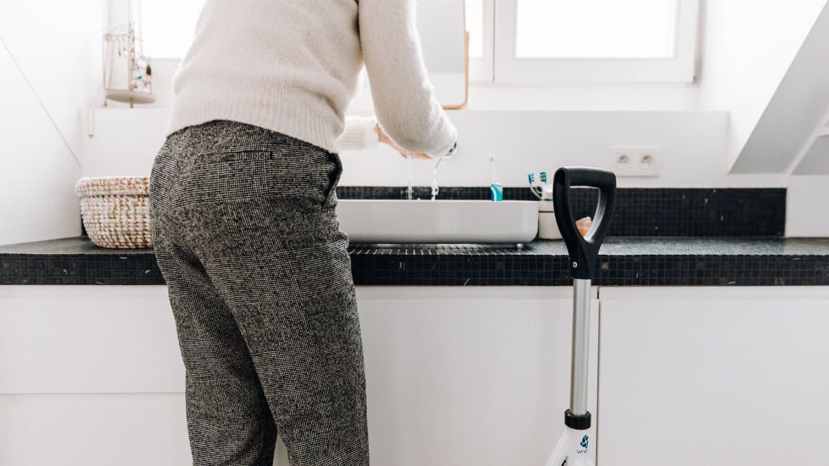 A senior adult using a rollator in a modern bathroom with sleek design elements.
