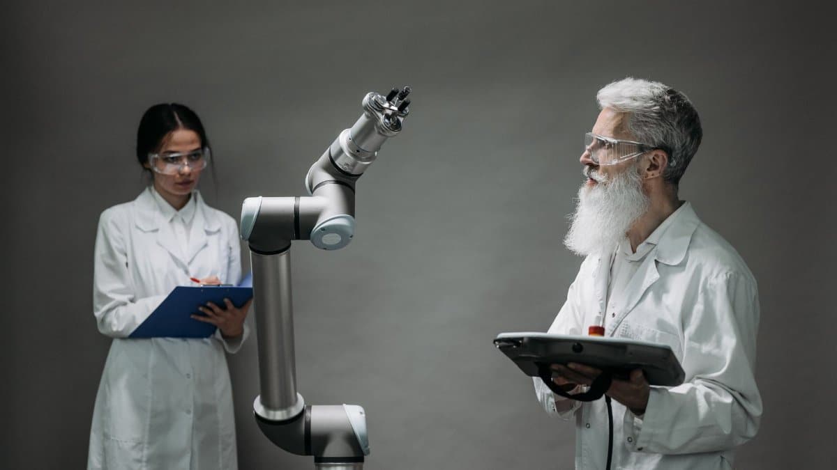 Two scientists working with a robotic arm in a lab setting, focusing on innovation and technology.