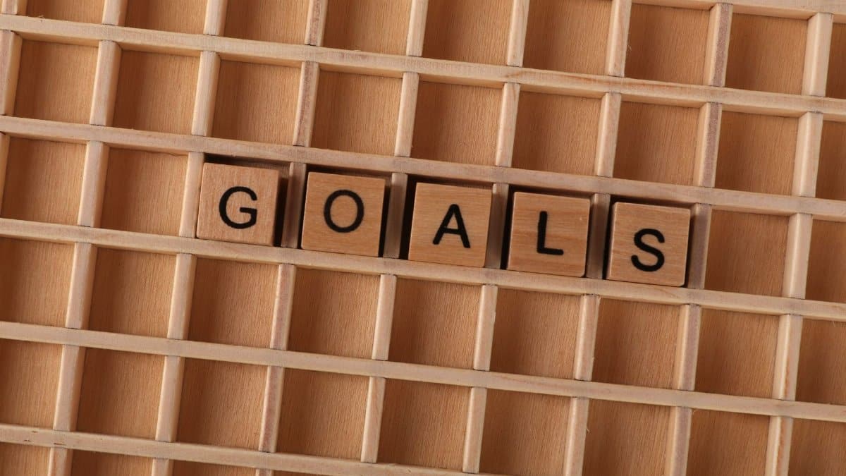 Wooden alphabet tiles spelling 'GOALS' on a grid background, symbolizing aspirations.
