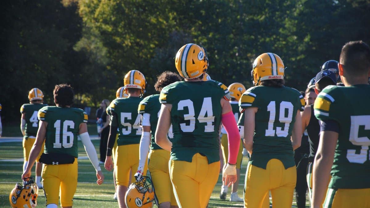 Football players in uniform walking on field during a sunny day game. Team sports action.