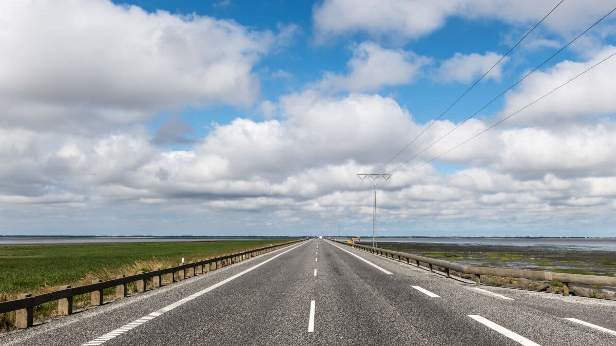 Empty countryside road in Rømø, Denmark stretching into the horizon under a vibrant cloudy sky.