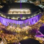 A vibrant night aerial view of Golden 1 Center in Sacramento, California during a lively event with a large crowd.