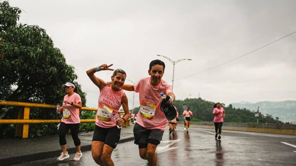 Group of runners in a marathon, smiling and enjoying a rainy day race.
