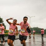 Group of runners in a marathon, smiling and enjoying a rainy day race.