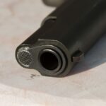 Detailed close-up of a gun barrel resting on a marble surface, highlighting the metal texture.