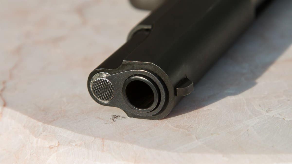 Detailed close-up of a gun barrel resting on a marble surface, highlighting the metal texture.
