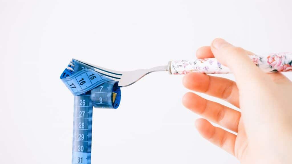 A floral-handled fork twirls a blue measuring tape, symbolizing diet and health.