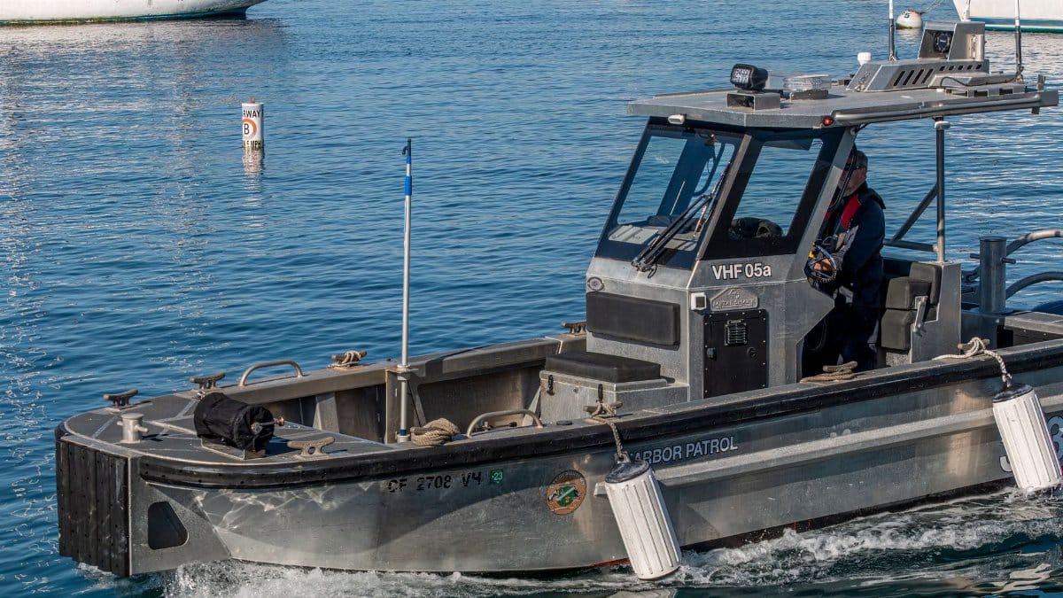 A harbor patrol boat cruising through calm blue waters, ensuring safety and security.