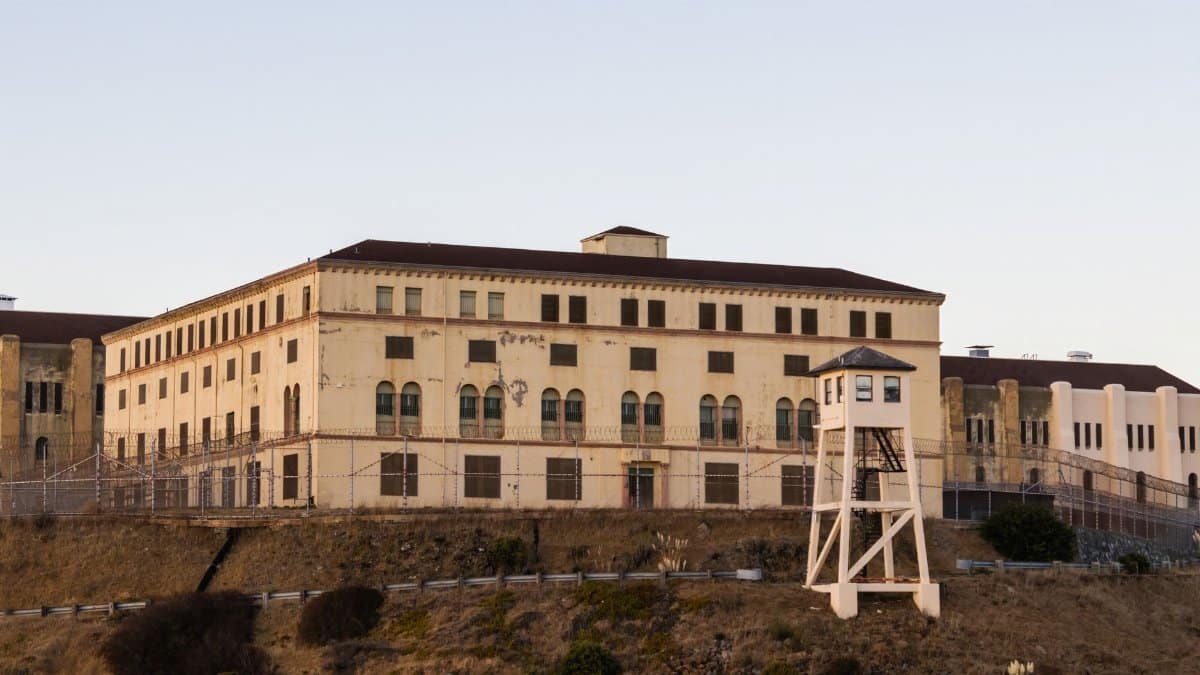 Exterior view of the historical San Quentin State Prison with a security tower at sunset.