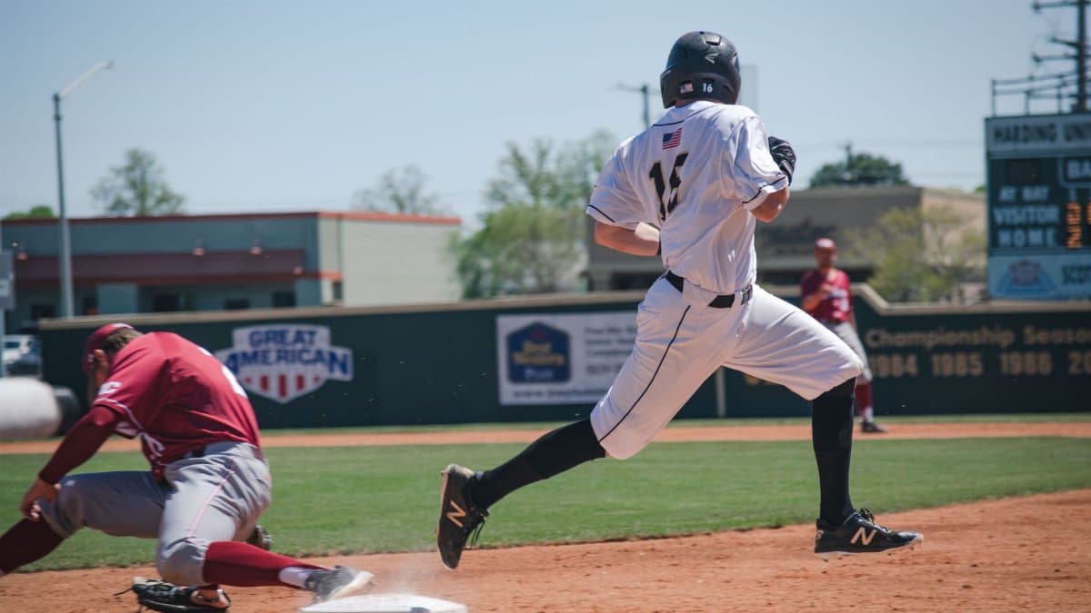 Two baseball players compete in an intense game at Harding University Stadium, showcasing sportsmanship and action.