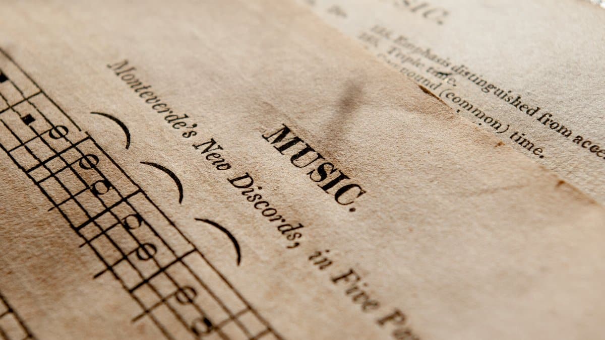 Detailed view of antique music sheets featuring notes and Monteverde's New Discords in sepia tone.