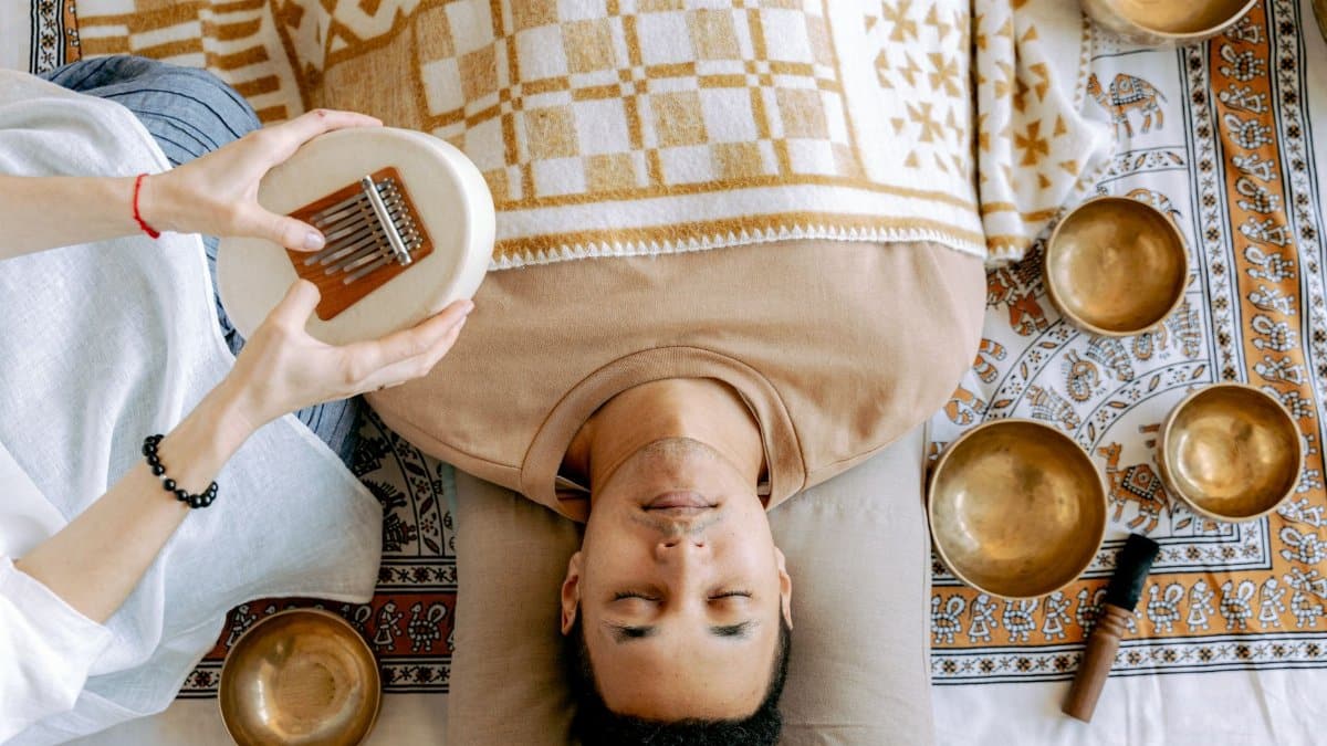 A serene sound bath session featuring a man relaxing with a kalimba and singing bowls.