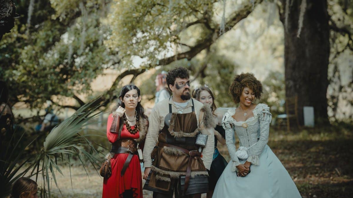 Medieval-themed group in costumes posing in a forest setting. Outdoor fantasy gathering.