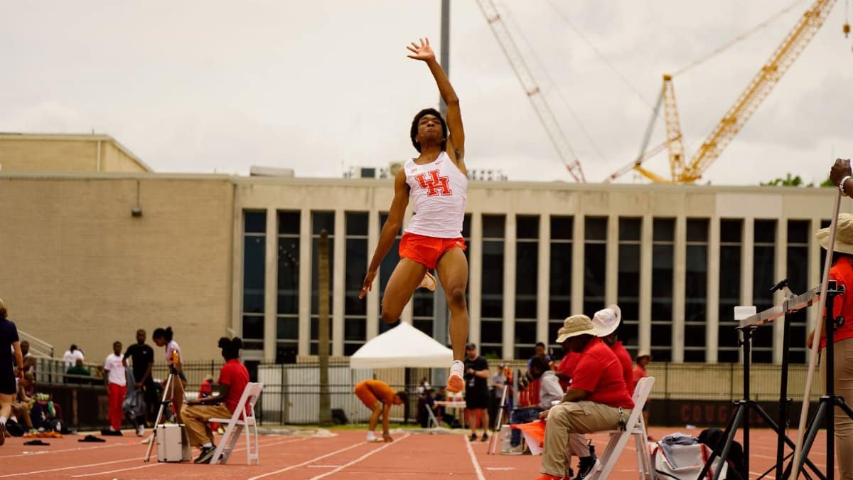 Male athlete performing a long jump at a track event in Houston, TX, showcasing athleticism and determination.