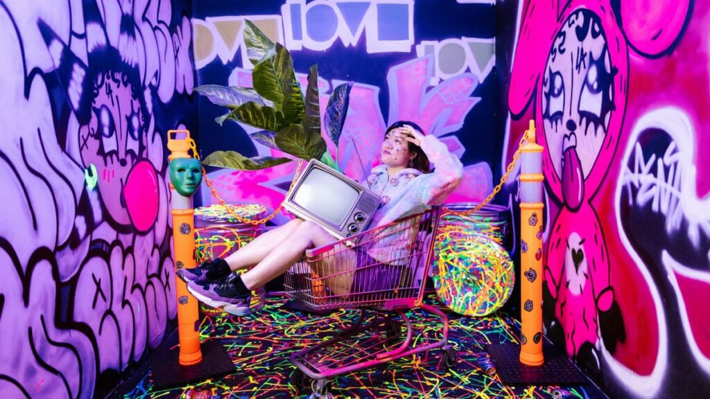 Creative fashion shot in a graffiti-filled room with a shopping cart and neon colors.