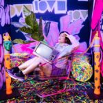 Creative fashion shot in a graffiti-filled room with a shopping cart and neon colors.