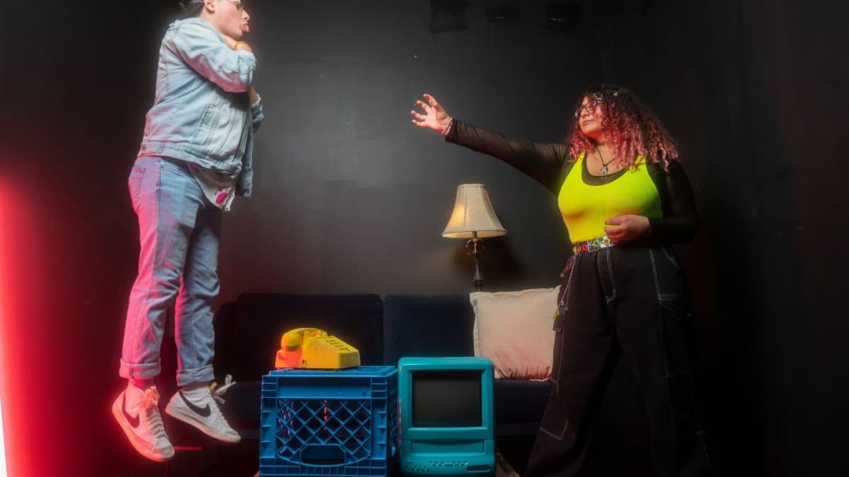 Two people in an artistic, creative setting with vintage electronics and vibrant fashion.