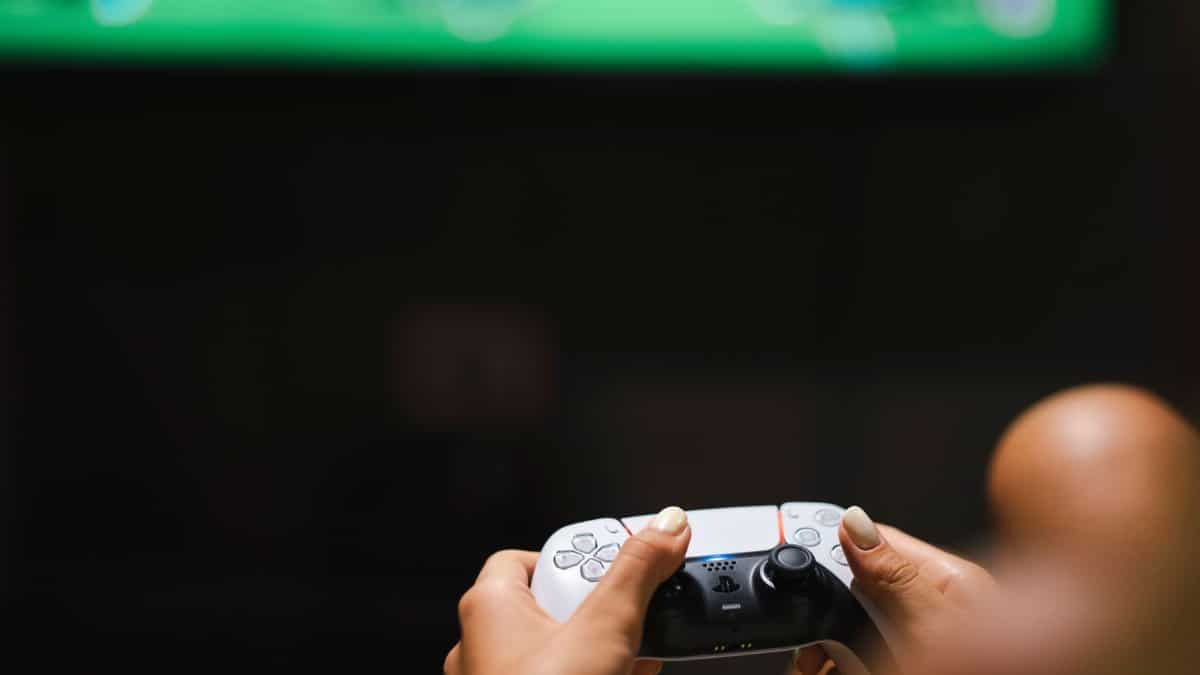 Close-up of hands holding a modern video game controller while gaming.