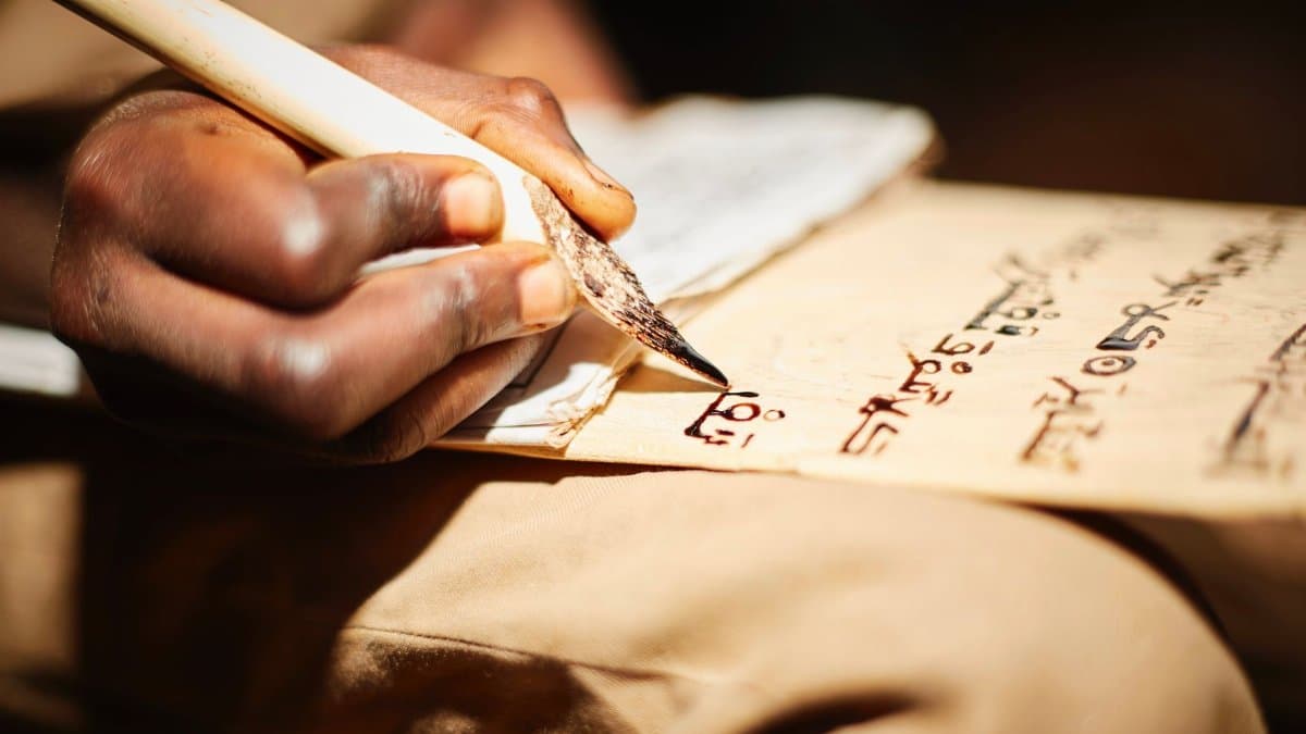 Detailed close-up of a person writing on papyrus with a traditional ink pen, highlighting cultural script.