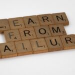 Wooden Scrabble tiles spelling 'Learn from Failure' on a white background, promoting resilience.