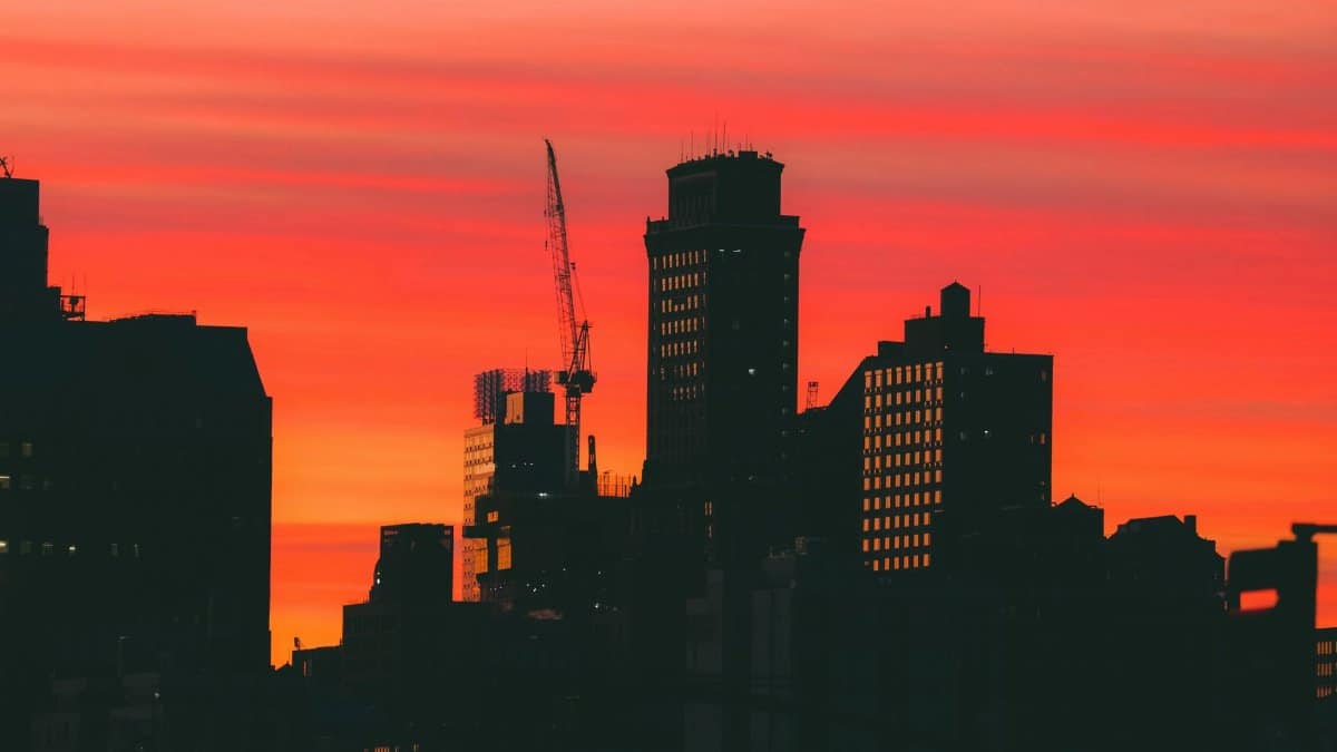 Silhouetted skyscrapers against a vivid New York sunset, showcasing iconic skyline beauty.