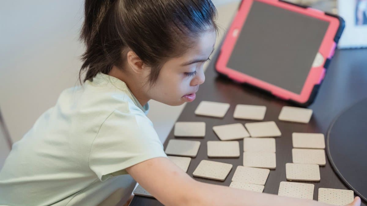 A young girl intently plays a memory card game indoors, showcasing focus and concentration.