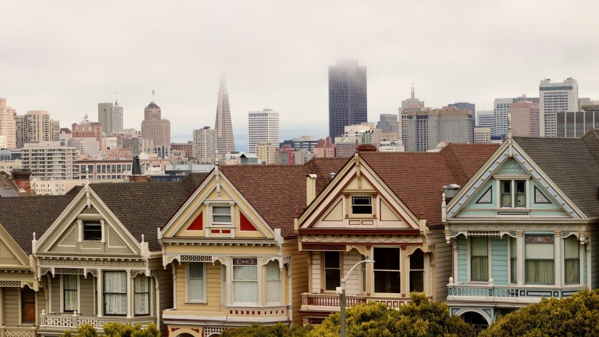 Iconic Painted Ladies in San Francisco with city skyline and fog.