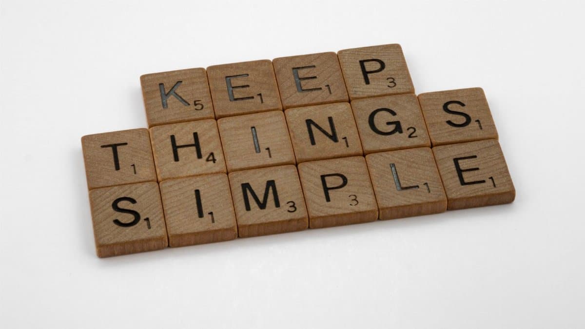 Motivational phrase 'Keep Things Simple' spelled out with wooden Scrabble tiles on a white background.