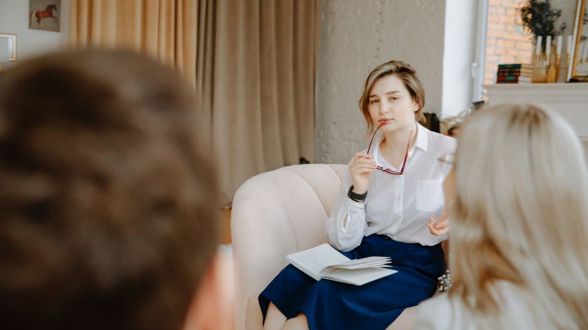 Counselor in a therapy session, attentively listening to clients indoors.