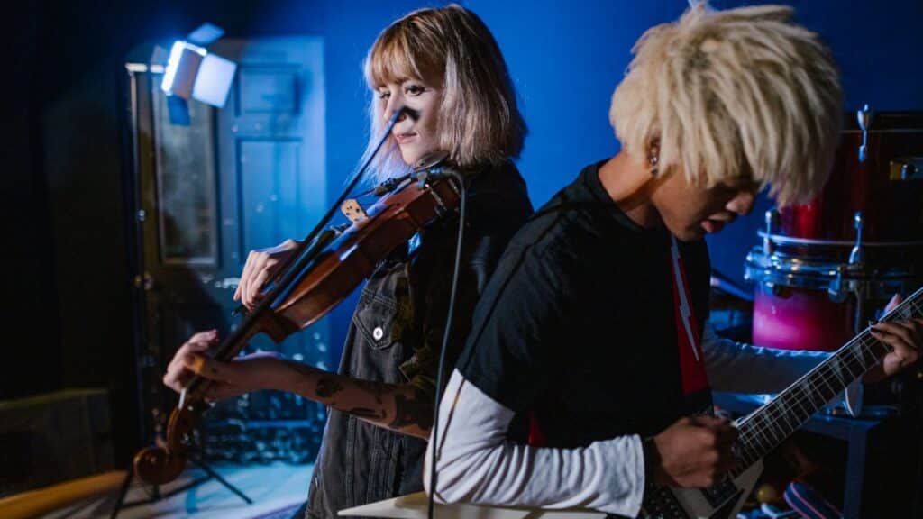 Energetic music rehearsal with violin and electric guitar under studio lighting.