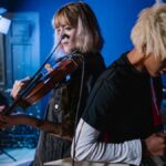Energetic music rehearsal with violin and electric guitar under studio lighting.