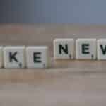 Scrabble tiles spelling 'Fake News' on a wooden surface highlighting misinformation.