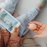 Young child engrossed in a smartphone video while holding a brain model indoors.