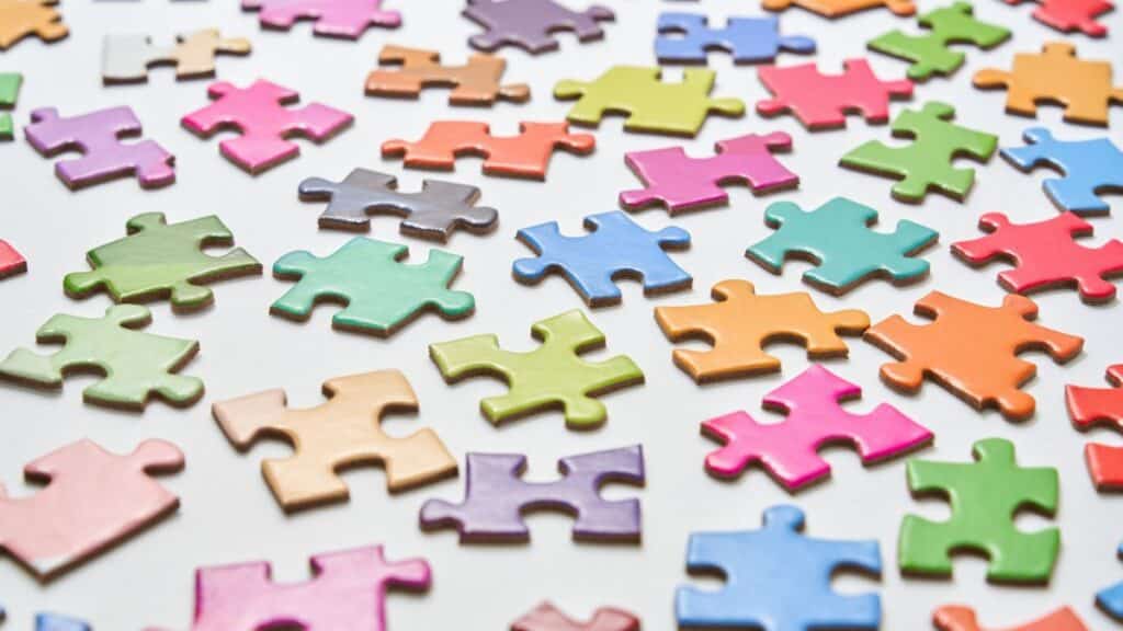Vibrant jigsaw puzzle pieces scattered on a white background in a still life composition.