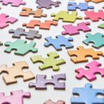 Vibrant jigsaw puzzle pieces scattered on a white background in a still life composition.