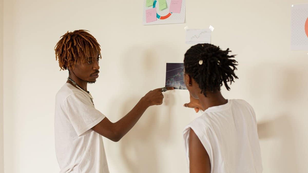 Two professionals discussing project management ideas using visual aids on a wall.