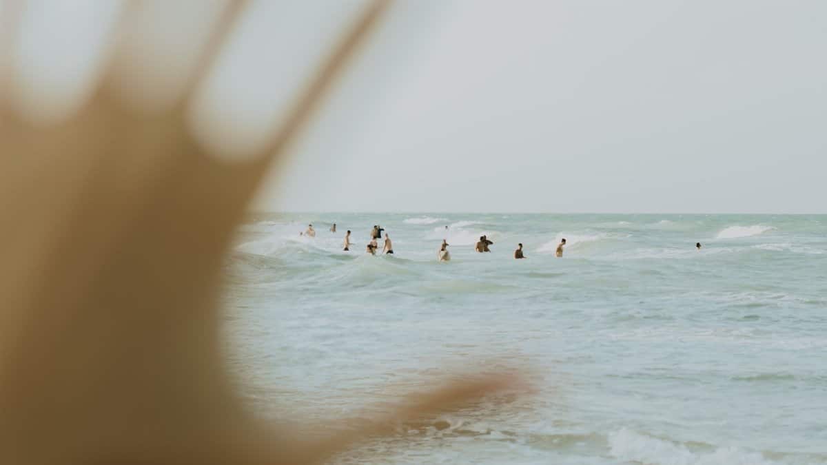 Soft focus beach scene capturing people enjoying the clear blue ocean waves under a warm sky.