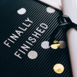 Close-up of a graduation diploma and letter board with "Finally Finished," surrounded by confetti.