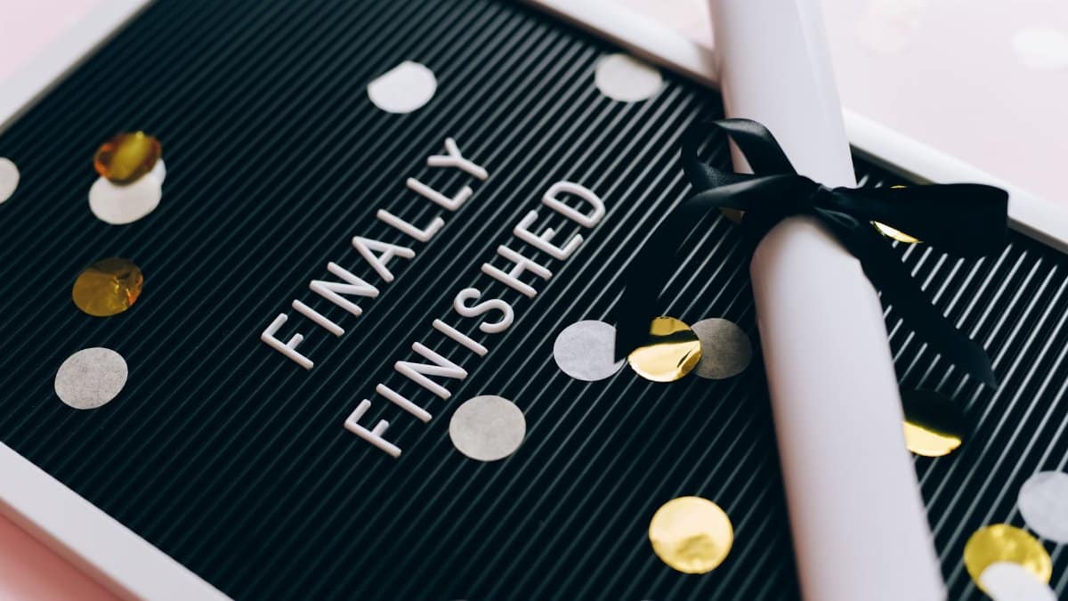 Close-up of a graduation diploma and letter board with "Finally Finished," surrounded by confetti.