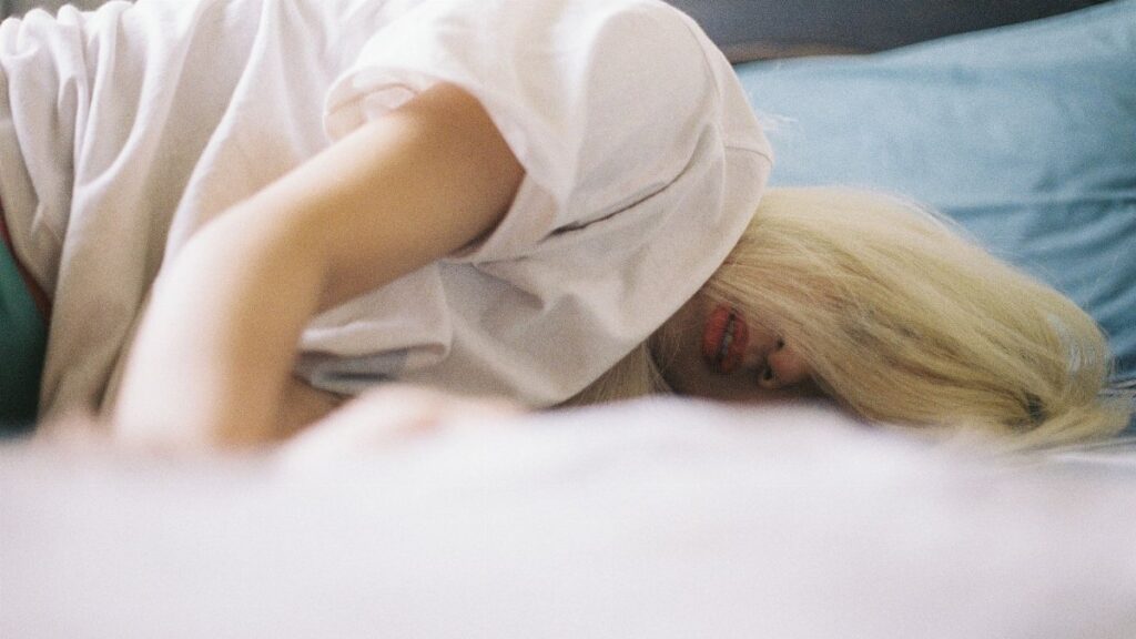 A woman with blonde hair lying on a bed, capturing a serene moment of relaxation.