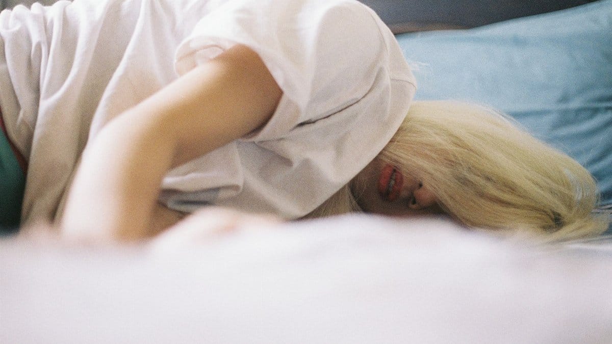 A woman with blonde hair lying on a bed, capturing a serene moment of relaxation.